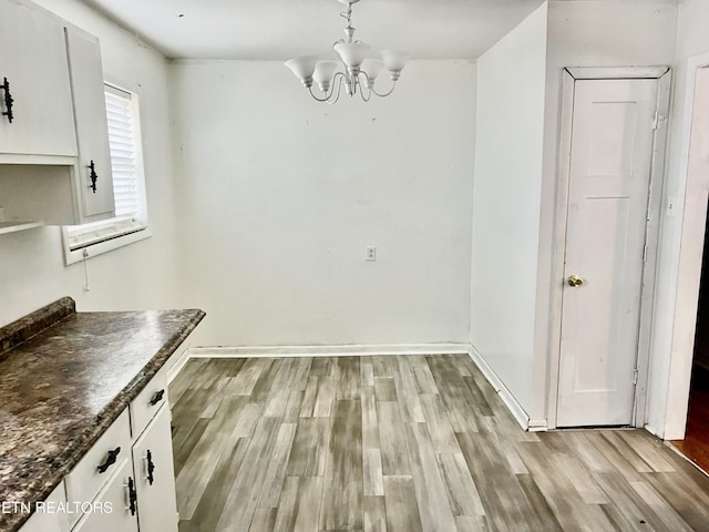 unfurnished dining area featuring light hardwood / wood-style flooring and a notable chandelier