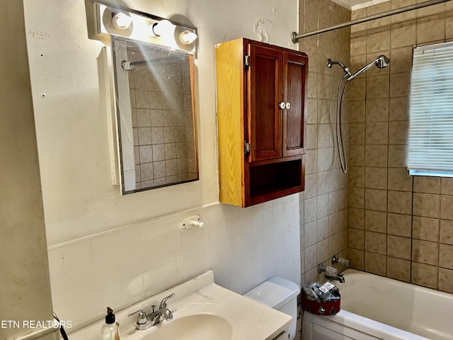 full bathroom with vanity, toilet, tile walls, and tiled shower / bath