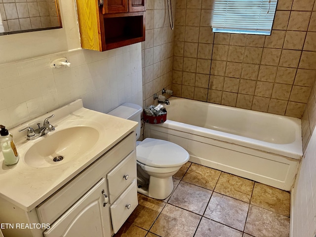 full bathroom featuring tiled shower / bath, vanity, tile walls, and toilet