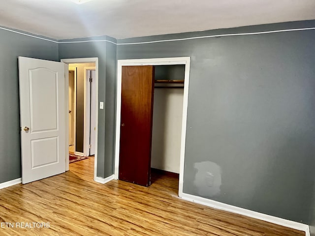 unfurnished bedroom with light hardwood / wood-style flooring and a closet