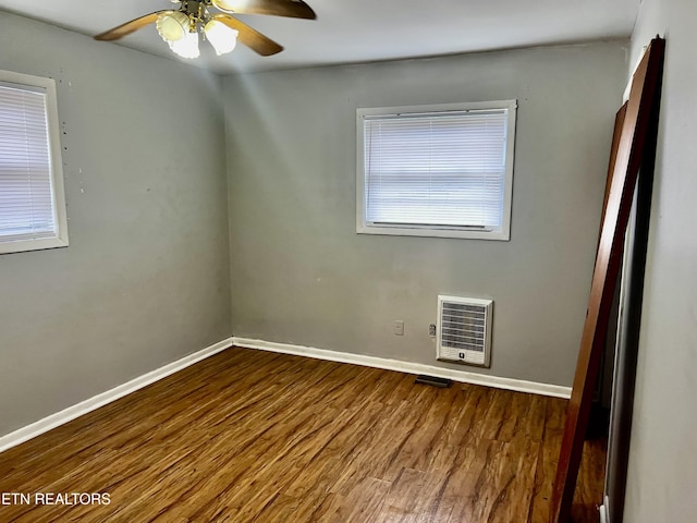 unfurnished room featuring heating unit, ceiling fan, and dark hardwood / wood-style floors