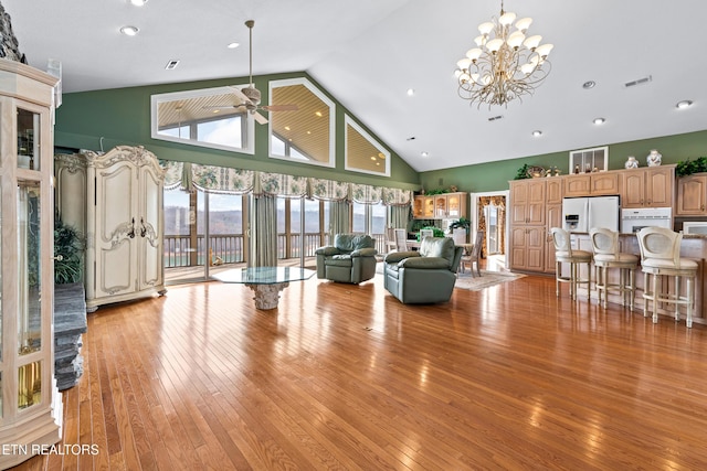 living room featuring ceiling fan with notable chandelier, light hardwood / wood-style floors, and high vaulted ceiling