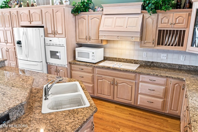 kitchen with light brown cabinetry, sink, white appliances, and light wood-type flooring