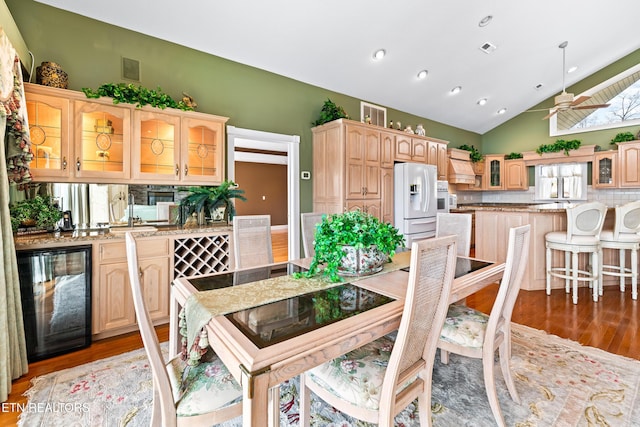 dining area with wine cooler, high vaulted ceiling, light hardwood / wood-style flooring, and ceiling fan