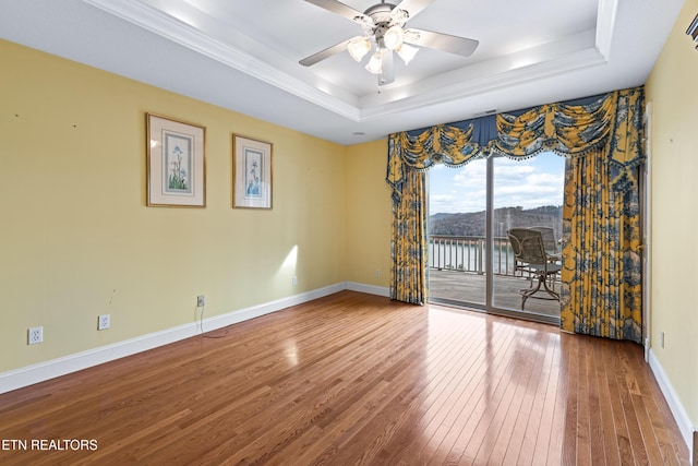 empty room featuring wood-type flooring, a tray ceiling, and ceiling fan