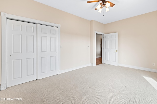 unfurnished bedroom featuring ceiling fan, a closet, and light carpet