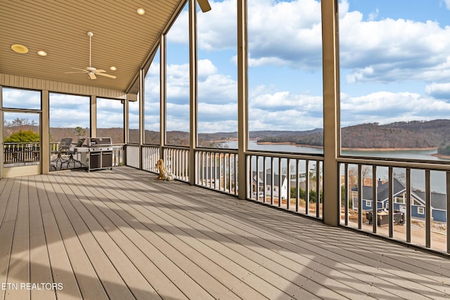 unfurnished sunroom with ceiling fan, a water and mountain view, and wooden ceiling