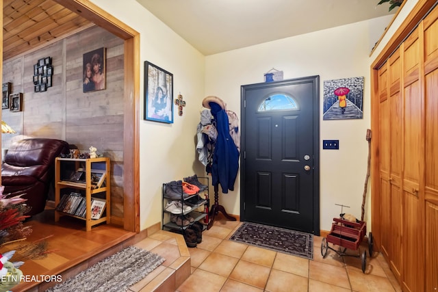 foyer featuring light tile patterned floors and wooden walls