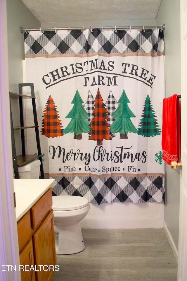 full bathroom with hardwood / wood-style floors, vanity, toilet, and shower / bath combo with shower curtain