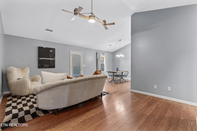 living room featuring vaulted ceiling, ceiling fan with notable chandelier, and hardwood / wood-style floors