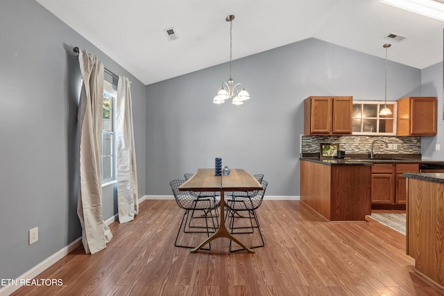 dining area with vaulted ceiling, a chandelier, light wood-type flooring, and sink