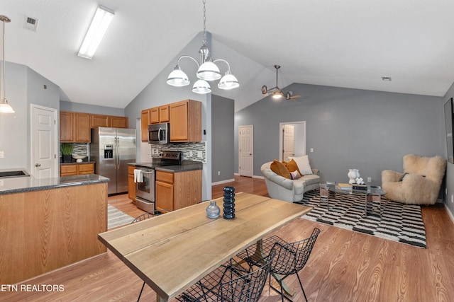 kitchen featuring stainless steel appliances, decorative backsplash, light hardwood / wood-style flooring, and decorative light fixtures