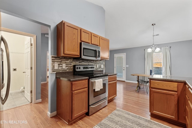 kitchen featuring an inviting chandelier, appliances with stainless steel finishes, decorative backsplash, pendant lighting, and light hardwood / wood-style flooring