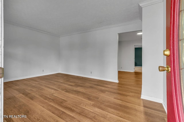 empty room with hardwood / wood-style flooring and crown molding