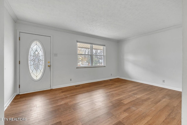 foyer entrance featuring light hardwood / wood-style floors, ornamental molding, and a textured ceiling