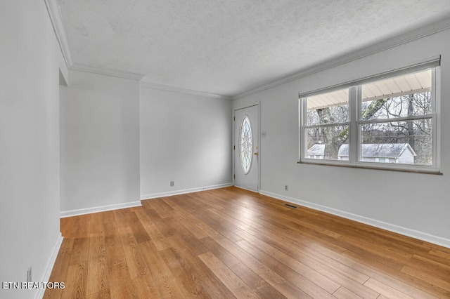 entryway featuring a textured ceiling, light wood-type flooring, and crown molding