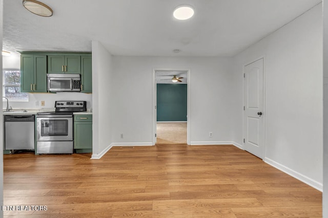 kitchen with green cabinets, ceiling fan, light hardwood / wood-style floors, and appliances with stainless steel finishes