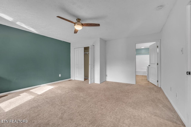 unfurnished bedroom featuring ceiling fan, light colored carpet, a textured ceiling, and a closet