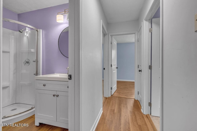 bathroom with hardwood / wood-style floors, vanity, and an enclosed shower