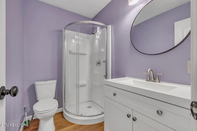 bathroom with hardwood / wood-style floors, vanity, toilet, and an enclosed shower