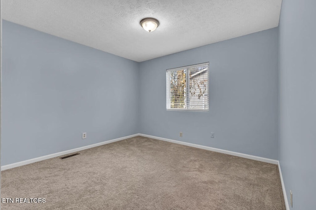 empty room with carpet floors and a textured ceiling