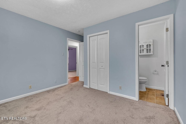 unfurnished bedroom with connected bathroom, a closet, light colored carpet, and a textured ceiling