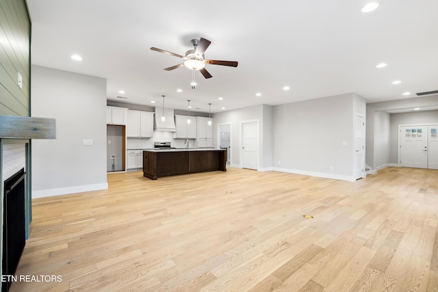 living room featuring light wood-type flooring, ceiling fan, and sink