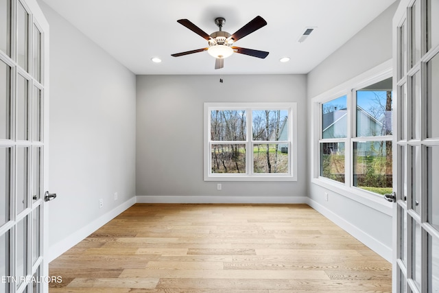 empty room with french doors, a healthy amount of sunlight, and light hardwood / wood-style flooring