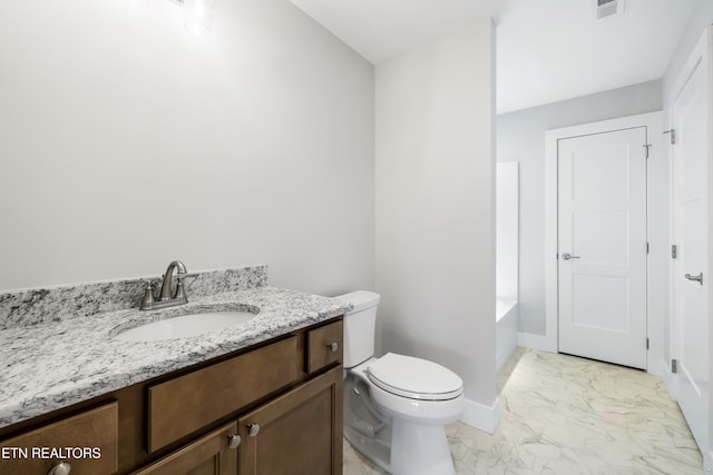 bathroom with a tub, vanity, and toilet