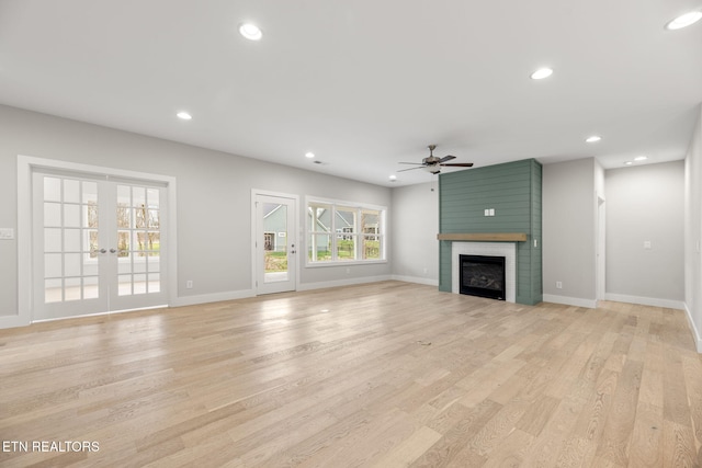 unfurnished living room with ceiling fan, a fireplace, light hardwood / wood-style floors, and french doors