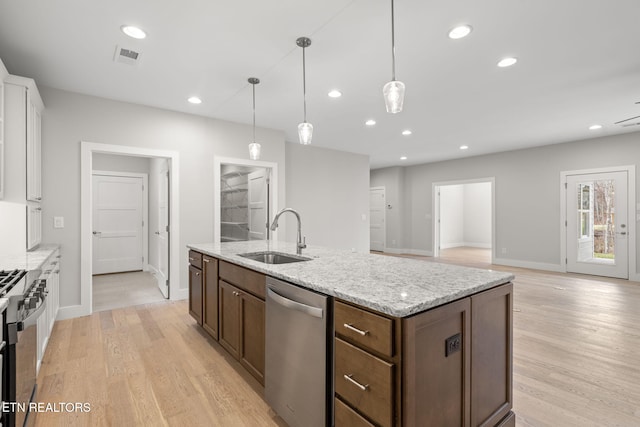 kitchen featuring light stone countertops, appliances with stainless steel finishes, sink, decorative light fixtures, and light hardwood / wood-style floors