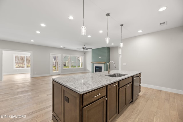 kitchen featuring ceiling fan, sink, light stone counters, stainless steel dishwasher, and pendant lighting