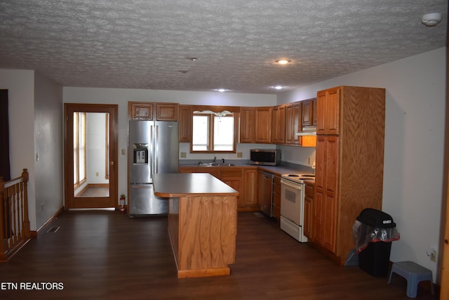 kitchen with a center island, sink, a textured ceiling, dark hardwood / wood-style flooring, and stainless steel appliances