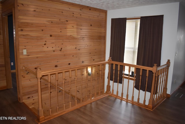 stairs featuring wood walls, hardwood / wood-style floors, and a textured ceiling