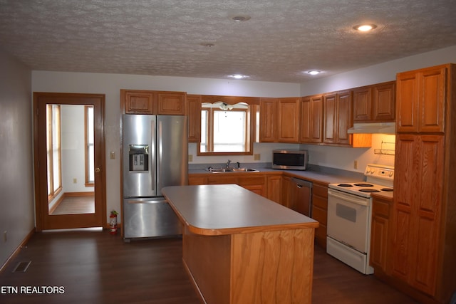 kitchen featuring a textured ceiling, stainless steel appliances, dark wood-type flooring, sink, and a kitchen island