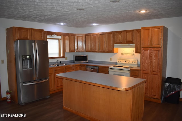 kitchen featuring sink, dark hardwood / wood-style floors, a textured ceiling, a kitchen island, and appliances with stainless steel finishes