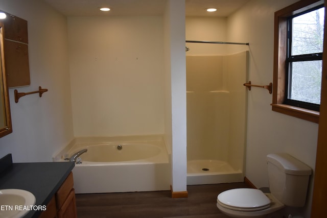 full bathroom featuring vanity, toilet, wood-type flooring, and shower with separate bathtub