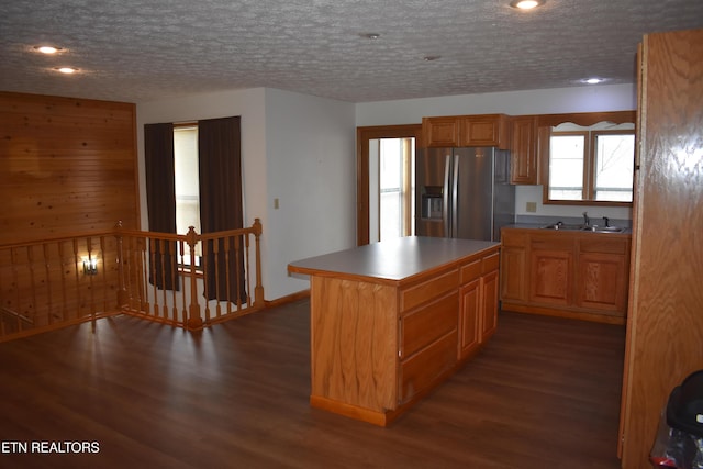 kitchen with stainless steel fridge, dark hardwood / wood-style floors, a kitchen island, and a textured ceiling