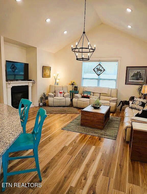 living room featuring a notable chandelier, vaulted ceiling, and hardwood / wood-style floors