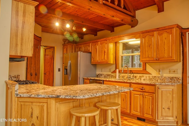 kitchen with beam ceiling, sink, stainless steel appliances, kitchen peninsula, and a breakfast bar area