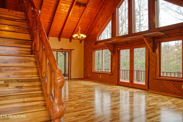 unfurnished living room with light wood-type flooring, wood ceiling, high vaulted ceiling, beamed ceiling, and a chandelier