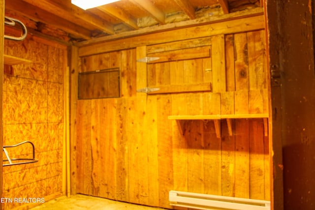 interior space featuring baseboard heating and wooden walls