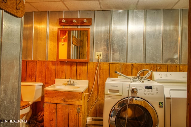 laundry area featuring washer and dryer, sink, and wooden walls