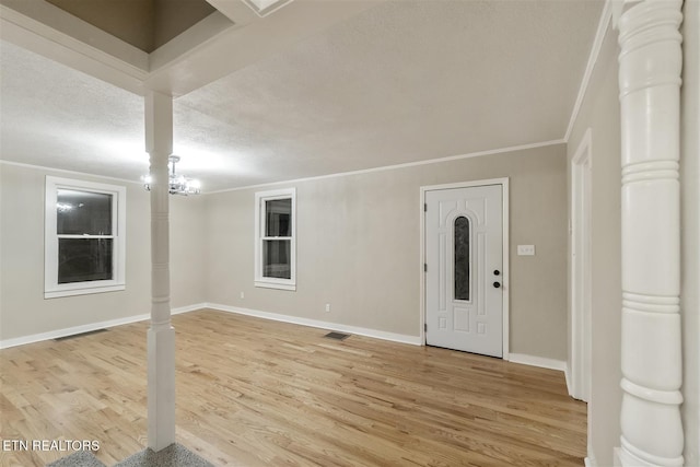 entrance foyer with wood-type flooring, a textured ceiling, and crown molding