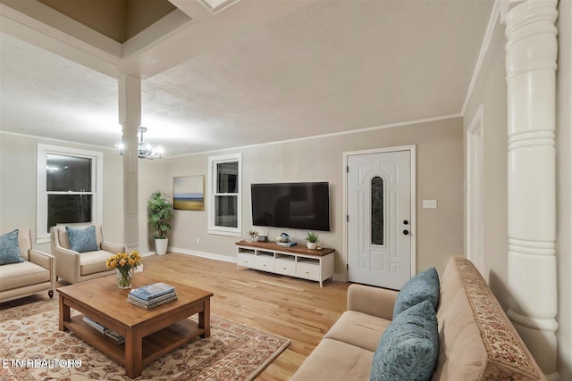 living room featuring ornamental molding, ornate columns, light wood-type flooring, a textured ceiling, and a chandelier