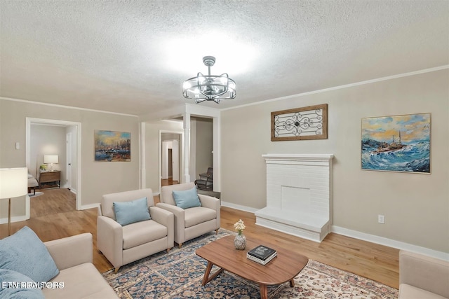 living room with a chandelier, wood-type flooring, a textured ceiling, and ornamental molding