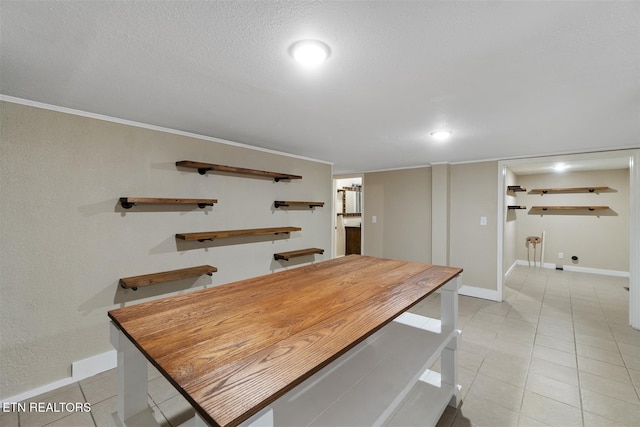 dining space featuring a textured ceiling, ornamental molding, and light tile patterned flooring