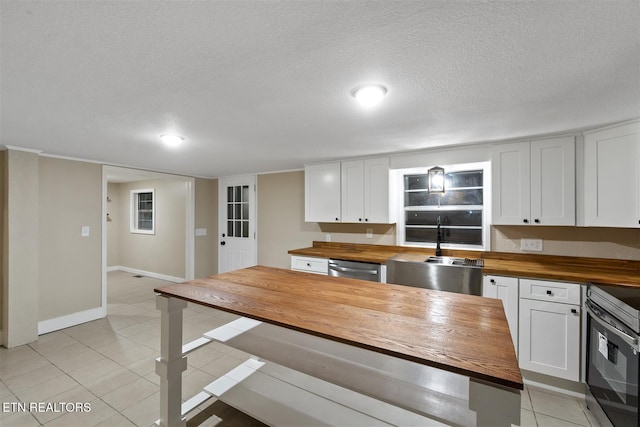 kitchen featuring a textured ceiling, wood counters, white cabinetry, and stainless steel appliances