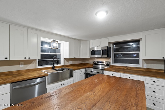 kitchen featuring stainless steel appliances, white cabinetry, sink, and wooden counters