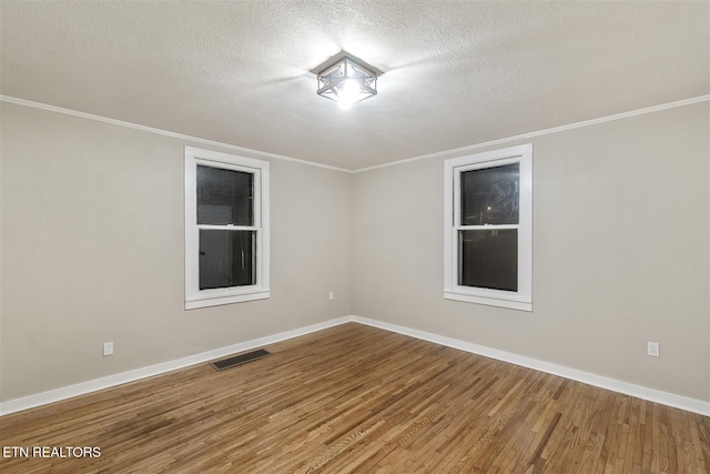 spare room with wood-type flooring, a textured ceiling, and ornamental molding